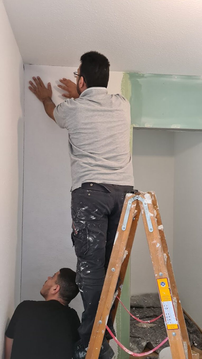 Maler Karlsruhe beim Spachteln einer weißen Wand im renovierten Flur mit Laminatboden